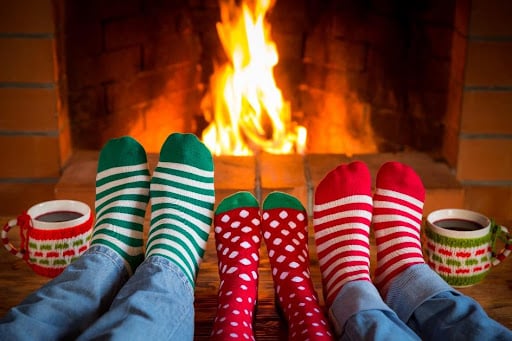 A family wearing festive socks enjoys curling up by their fireplace to stay warm during the winter in their Newark, OH home.